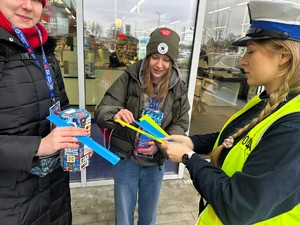 Policjantka wręcza odblaski wolontariuszą.