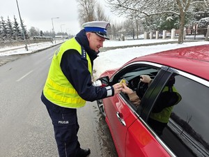 Policjant wręcza zawieszkę kierującemu.