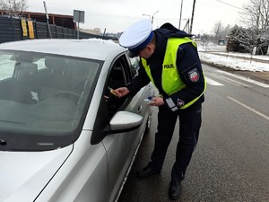 Policjant wręcza zawieszkę zapachową z napisem zwolnij.