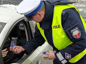 Policjant wręcza zawieszkę zapachową z napisem zwolnij.