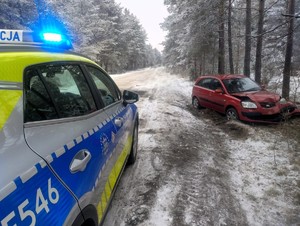 Na drodze stoi policyjny samochód. Po prawej stronie widać uszkodzony samochód marki KIA.