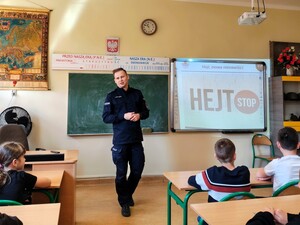 Policjant rozmawia z uczniami. Dzieci siedzą przed stojącym policjantem.