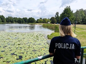 Policjantka obserwuje brzeg zbiornika wodnego.