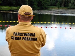 Strażak stoi na plaży i ogląda kąpielisko.