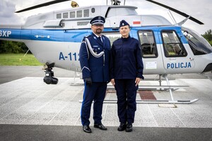 Nowa policjantka stoi razem z Komendantem przed policyjnym smigłowcem.