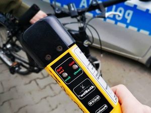 Alkomat, w tle rowerzysta i policyjny radiowóz.