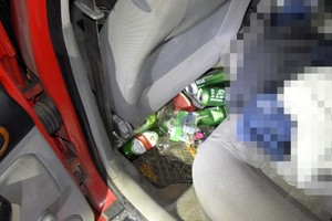 Na wycieraczce leżą puste puszki po piwie.