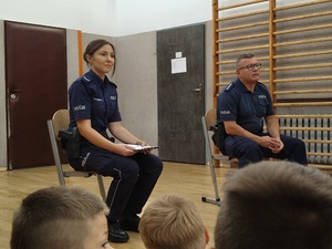policjanci w mundurach siedzący na krzesłach.
