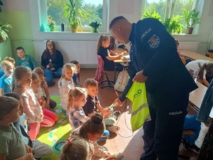 Policjant rozdaje dzieciom odblaski.