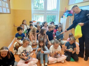 Policjant rozdaje dzieciom odblaski.