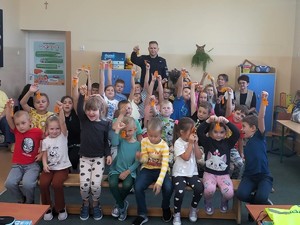 Policjant rozdaje dzieciom odblaski.