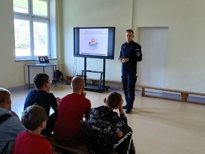 Policjant rozmawia z uczniami o przemocy.