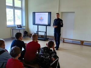 Policjant rozmawia z uczniami o przemocy.
