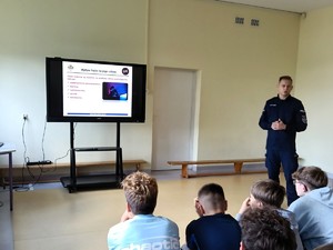 Policjant rozmawia z uczniami o przemocy.