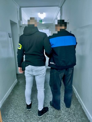Policjant stoi z osobą poszukiwaną.