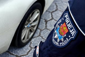 Policjant stoi przy aucie.