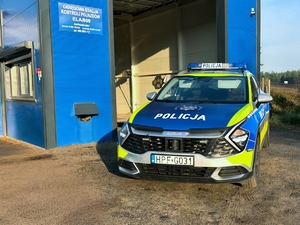 Policyjny radiowóz stoi przed stacją kontroli pojazdów.