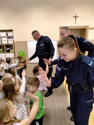 Policjanci rozmawiają z małymi dziećmi.