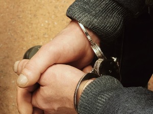 Policjanci trzymają pod rękę poszukiwanego.