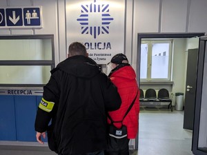 Policjanci trzymają pod rękę poszukiwanego.