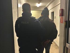 Policjant trzyma pod rękę zatrzymanego.