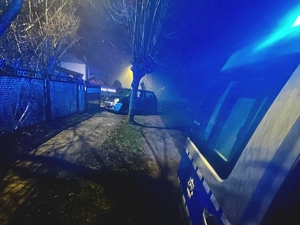 Pojazd zaparkowany na poboczu, w tle widać światła radiowozu.