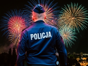 Policjant a w tle fajerwerki.
