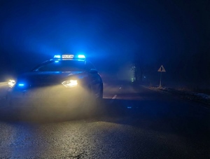 W nocy na drodze stoi policyjny samochód.