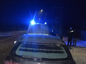 Przed autem stoi policyjny radiowóz.