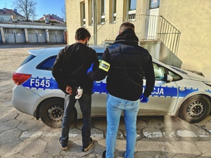 Policjant trzyma pod rękę poszukiwanego.