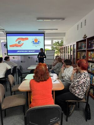 Policjantka rozmawia z seniorami o bezpieczeństwie.
