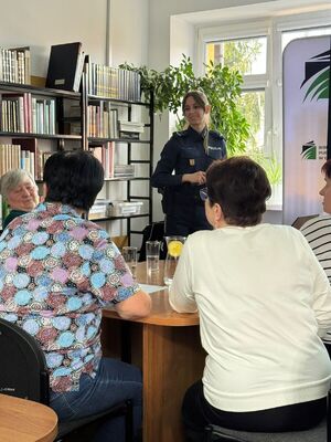 Policjantka rozmawia z seniorami o bezpieczeństwie.