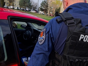 Policjant stoi przy samochodzie zatrzymanego.