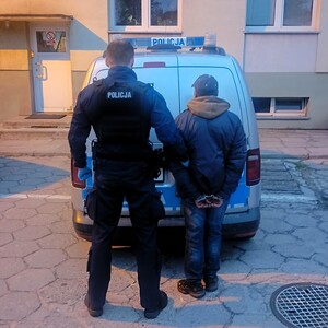 Policjant trzyma zatrzymanego.