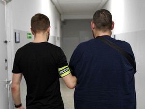 Policjant trzyma osobę zatrzymaną.