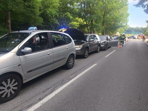 pojazd koloru szarego stojący na drodze, za nim inne auta. W oddali widoczny radiowóz policyjny.