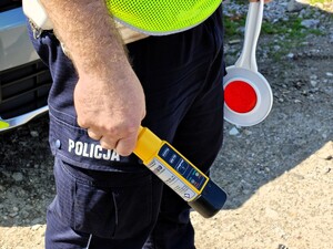 osoba w mundurze policyjnym w ręku trzymająca alkoblou oraz tarczę do zatrzymywania pojazdów.