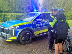 Policjanci rozdają kaski bezpieczeństwa.