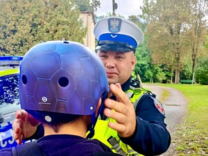 Policjanci rozdają kaski bezpieczeństwa.
