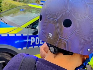 Policjanci rozdają kaski bezpieczeństwa.