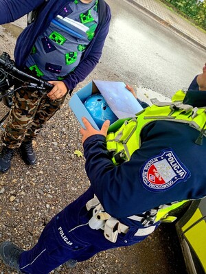 Policjanci rozdają kaski bezpieczeństwa.