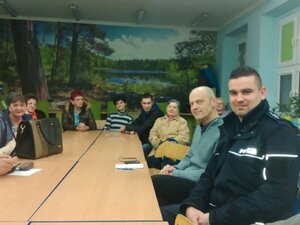 Dzielnicowy wraz z mieszkańcami siedzi przy stole.