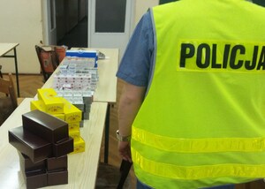 Policjant wykonuje czynności przy zabezpieczonych papierosach.